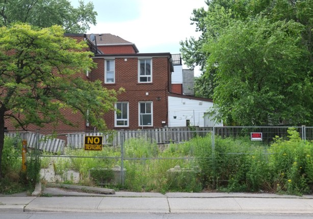 fence around vacant lot beside a brick house, no trespassing sign on fence