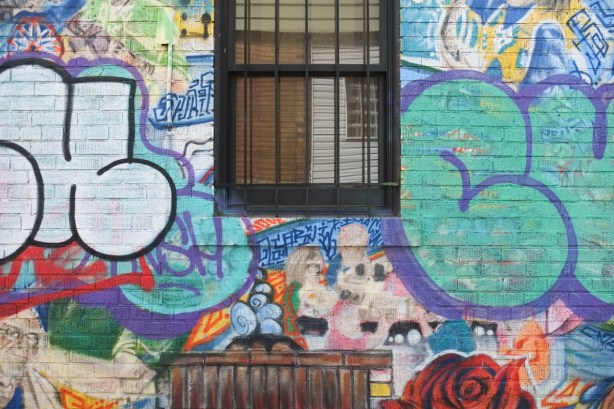 window in wall with street art that has been tagged over