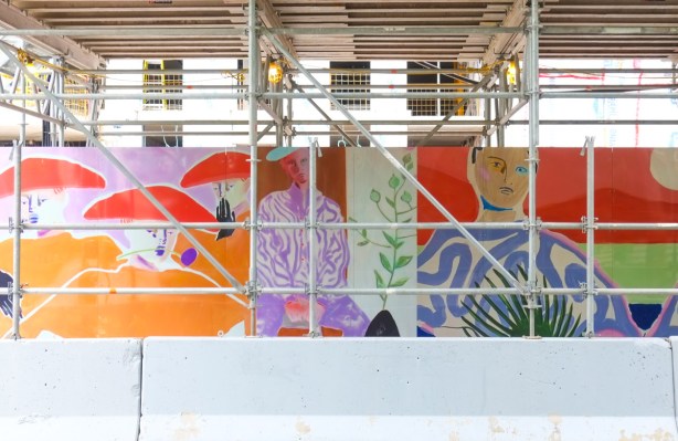 artwork on hoardings and under scaffolding, beside sidewalk, around construction site, people, with lots of purple and orange tones