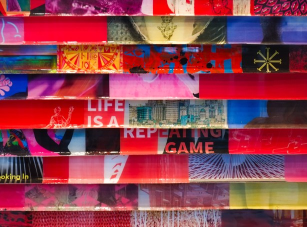 artwork in a gallery window, horizontal stripes, painted in abstract, with words life is a repeating game