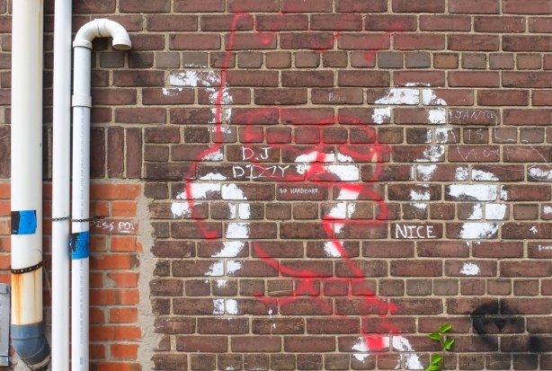 red brick wall with white spray paint question marks and some words written in white or black