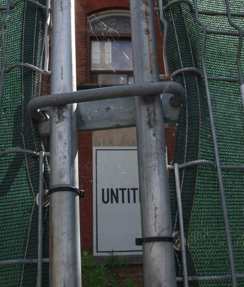 behind hoardings, boarded up house with graffiti sign by Nigel Smith that says untitled