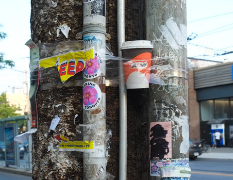 bits of old posters on a utility pole, an A and W coffee cup taped to the pole as well
