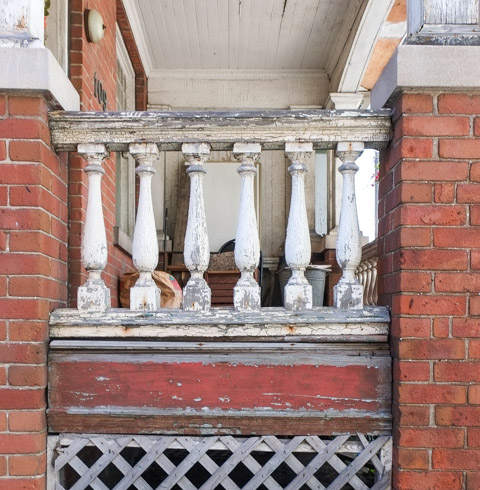 wood railing on a porch, old paint, white, brick house,