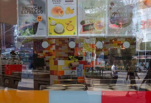 reflections in the window of an uncle tetsu cheesecake store