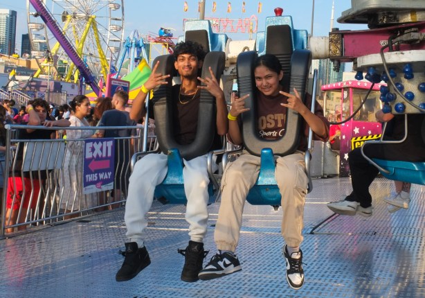 young couple sitting on a ride at the ex midway waiting for it to start