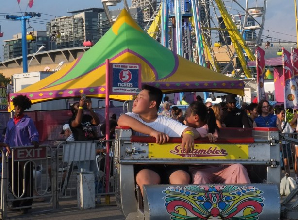 two people on scrambler ride at Canadian National Exhibition, evening 