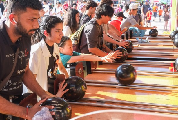 people playing roller bowler game where you roll a bowling ball to win a prize