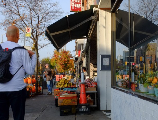 a man walks by a fruit and vegetable store on bloor street