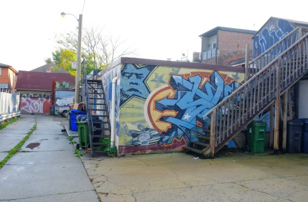 an alley in bloorcourt, murals on garage, staircases, brick buildngs,