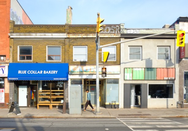 bloor west, north side, at brock, blue collar bakery, bar neon, old laundromat, man walking past on sidewalk,
