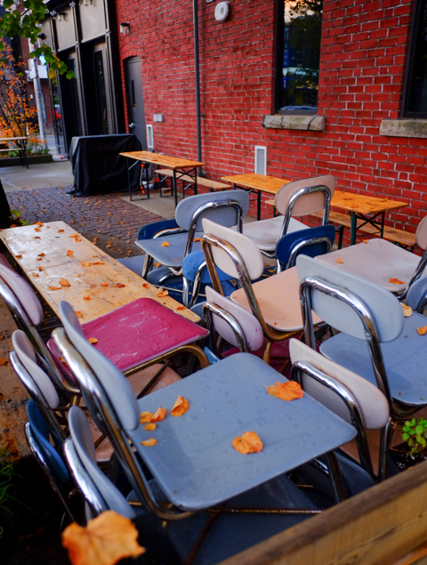 chairs stacked in corner of patio, outside, some leaves have fallen on the chairs