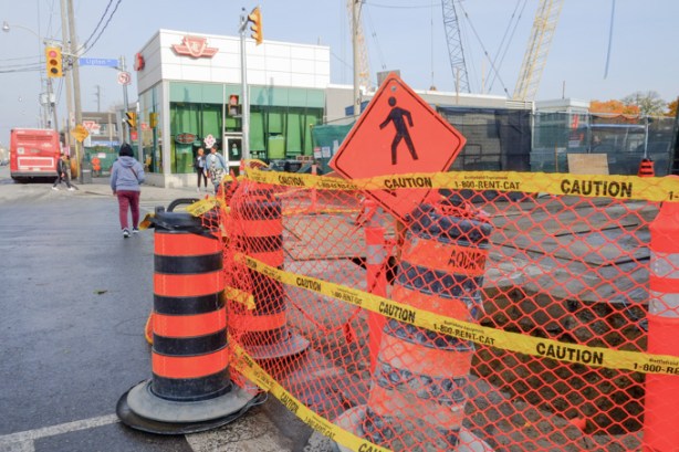 orange and black traffic cones, and orange construction mesh fencing, outside pape subway station, for ontario line construction