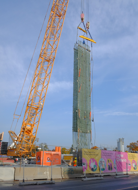 large yellow crane holds up an very large item, ontario line construction