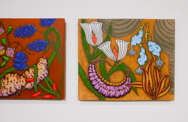 2 ceramic tiles mounted on a wall, in an art gallery, floral pictures