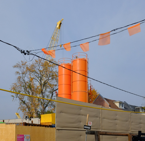 2 large orange storage tanks, wires, crane, ontario line construction site , orange flags on overhead wires