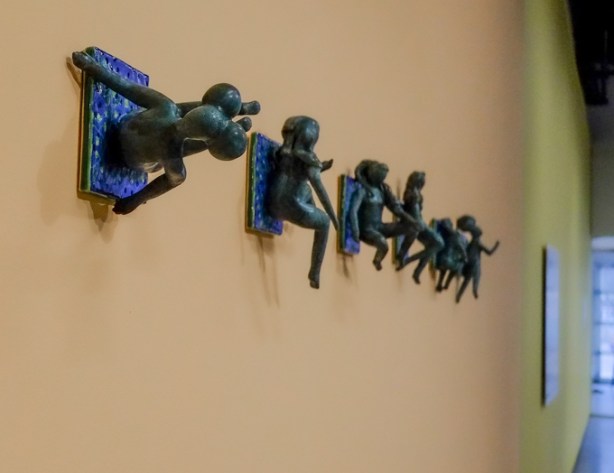small figurine of people in different positions, hanging on a wall