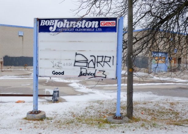 old sign for bob johnston chevrolet dealer on kingston road, graffiti on it