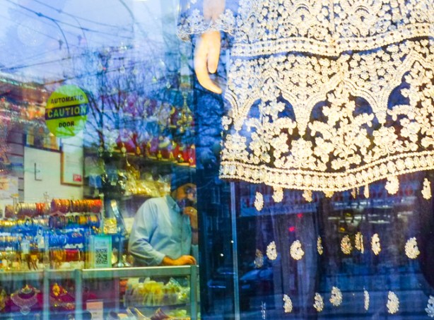 in store, man behind counter, looks out door as photo is being taken of mannequin in the window