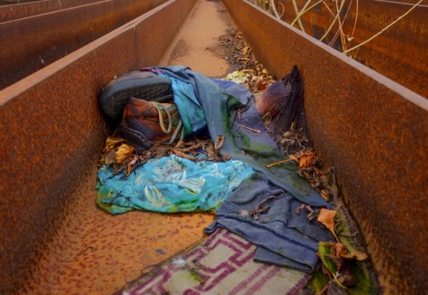 discarded pair of boots, and some clothing, left on metal girders stored beside a railway track