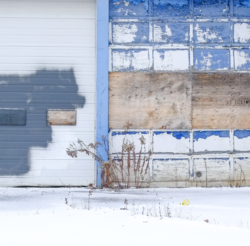 peeling blue paint on old garage door, snow in front