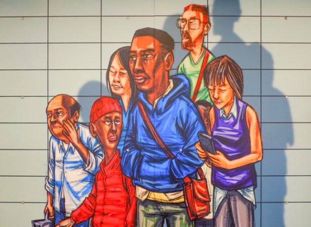 Elicser Elliot mural at Runnymede subway station, people walking, men and women, man in blue hoodie, woman holding phone, man in red hat and jacket 