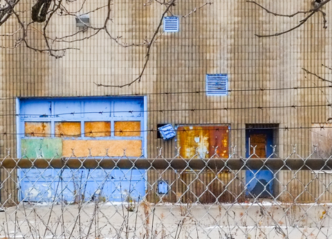 chainlink fence with abandoned building behind