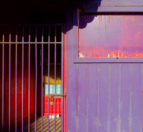 gate across entrance to true love cafe, red door, purple building, painted over window,