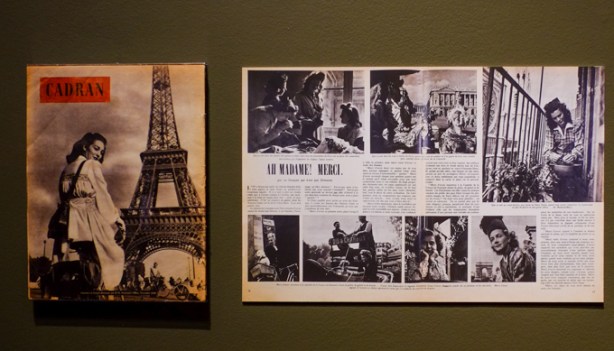 two photos on a gallery wall, on left is woman on a motorbike by the eiffel tower in Paris and on the right are a group of black and white photos of women working, article is thanking women for their role in winning world war 2