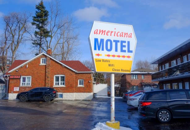 Americana Motel sign in yard of the motel, red brick buildings,