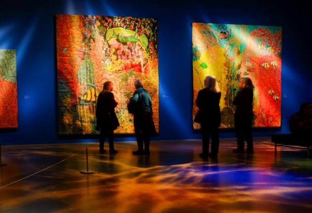people in an art gallery, Art Gallery of Ontario, looking at artwork by Pacita Abad, large fabric pieces in vibrant colors, of underwater scenes 