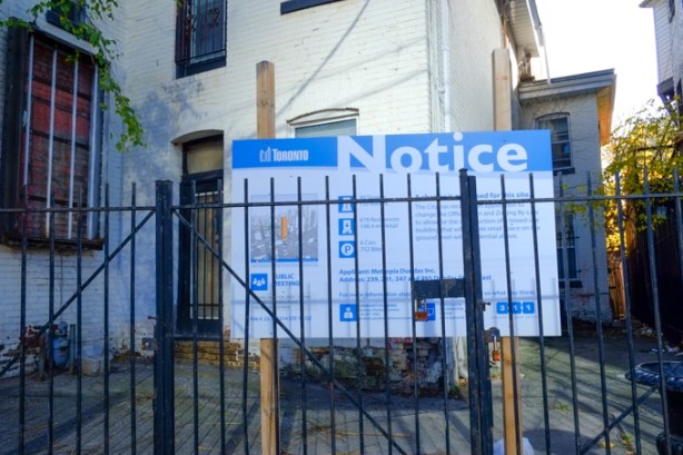 blue and white city of toronto development notice sign on front yard of a house on dundas east
