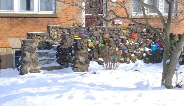 curved porch and front steps in front of a house where some of the rocks are painted bright colours