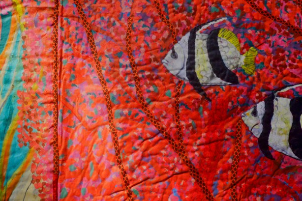 fabric artwork by Pacita Abad hanging at the Art Gallery of Ontario underwater scene, striped fish, colourful seaweed enhanced with striped braiding sewn on top of the painted mottled pink fabric, 