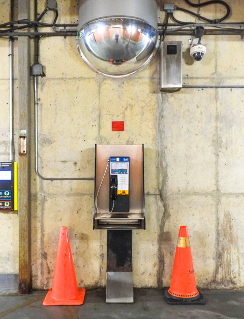 two orange cones beside a phone booth against a concrete wall, interior, wilson subway station