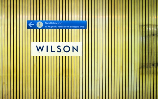 yellowish vertical cladding, interior wilson subway station, with blue sign with arrow pointing to the left for northbound trains