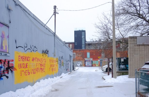 boland lane, looking towards back of dundas west, snow covered graffiti on walls of building on the left