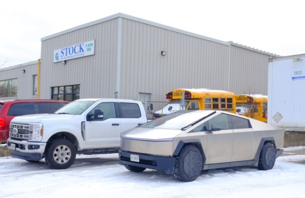 Tesla cybertruck parked by Stock school bus office building, small yellow school buses in the background.