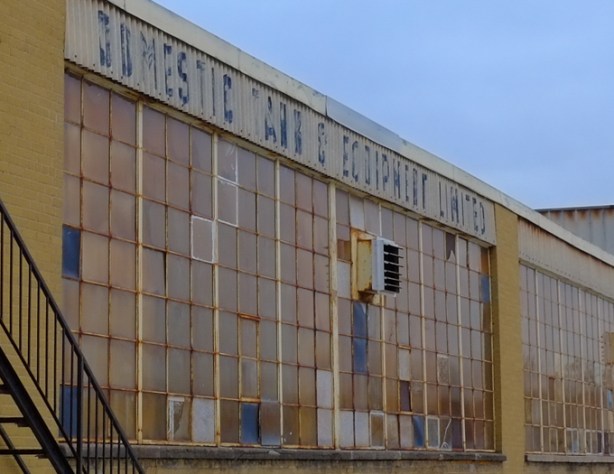 part of wall of windows at Domestic Tank and equipment factory, yellowish bricks with large windows made up of hundreds of small panes of window glass