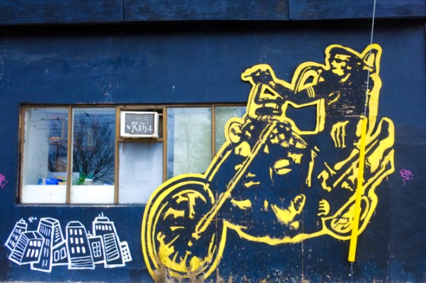 yellow painting of a man on a motorcycle, on wall outside Easy Restaurant, King street side