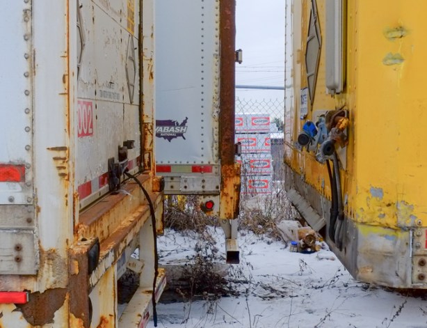 looking between the backs of trucks that are parked close to each other