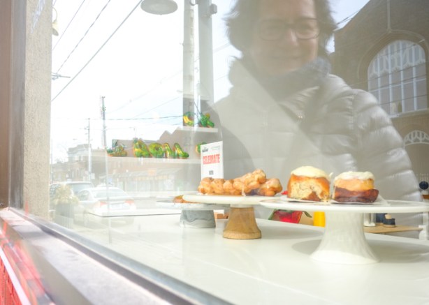 reflection of woman looking at pastries for sale in a bakery window, 