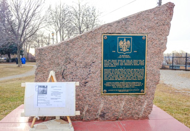 monument in a park, large stone with a plaque on it, 
