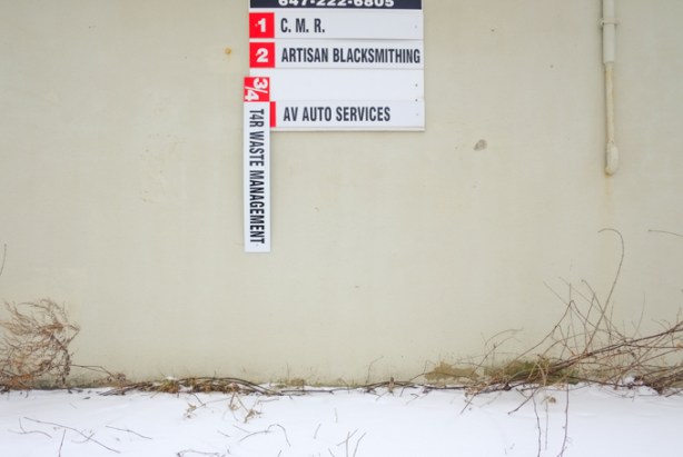 signs on the side of a building, one of the signs is partially fallen off