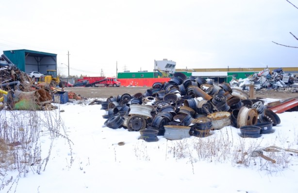 pile of old wheel rims, other piles of scrap metal and metal for recycling