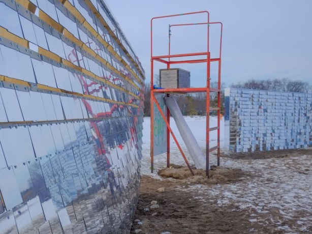 winter stations art installation, hundreds of little reflective squares that move in wind, reflecting beach and lake and sky , panels on both sides of a lifeguard station chair