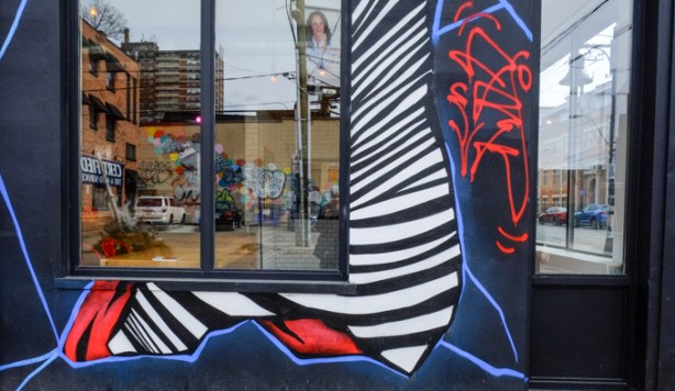 part of a street art mural that frames the windows in a store, reflections in the window