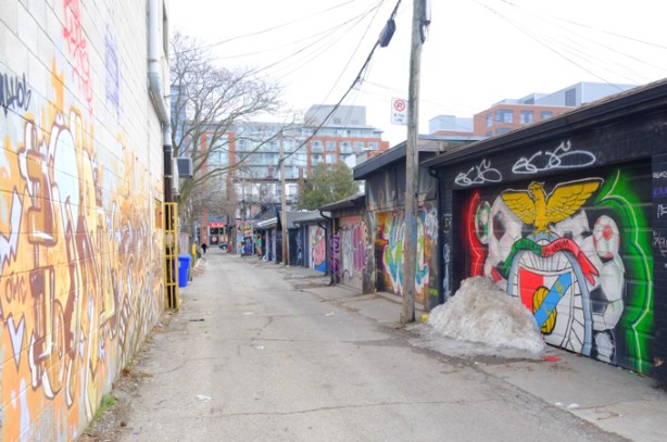 alley, with garages on one side, mural on the wall of a building on the left 