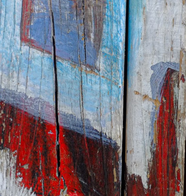 close up of painting on a wood fence, abstract shapes and colours, with texture