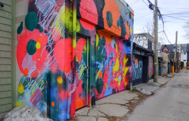 garage in alley covered with paintings of bright flowers